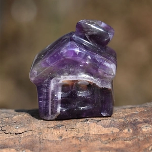 Detailed close-up of a house-shaped figurine carved from natural purple amethyst crystal