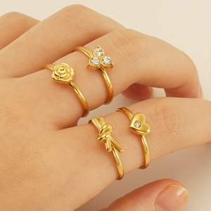Detail of 18K gold plated adjustable ring set featuring rose, heart and floral designs