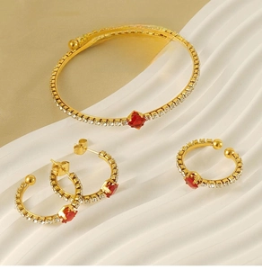Detail of 18k gold plated jewelry set with red ruby zircons on a luxury background