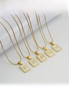 Detail of 18K gold plated stainless steel square zodiac pendants on snake chains