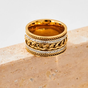 Macro view of wide gold-plated stainless steel ring with rhinestones and chain detail