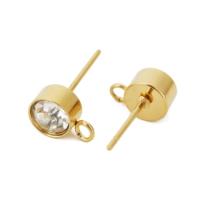 Détail macro de clous d'oreilles plaqués or avec zircons clairs et boucles latérales