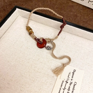 Detail of hand-woven ceramic bracelet with red agate pendant and elegant tassels