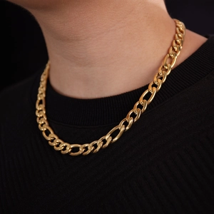 Close-up of gold Figaro chain necklace on male model wearing black knitwear