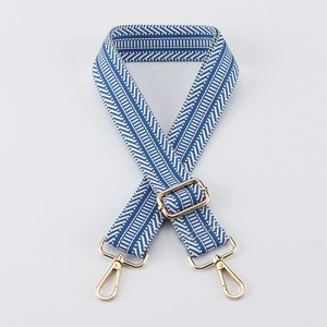 Detail of blue and white striped herringbone bag strap with gold metal hooks and buckle