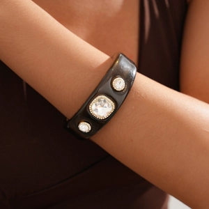 Detail of vintage wide resin cuff with large crystals on model wrist for high-end look