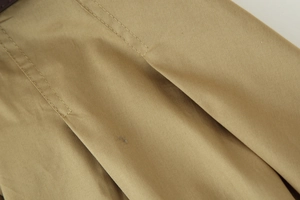 Détail du tissu en coton kaki montrant la texture et la qualité des doubles coutures nettes