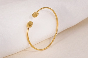Macro view of gold open bangle featuring Hope engraving and Tree of Life symbol