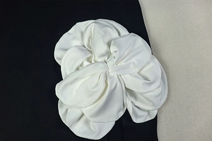 Dettaglio macro di applicazione floreale 3D in tessuto bianco con trama in seta