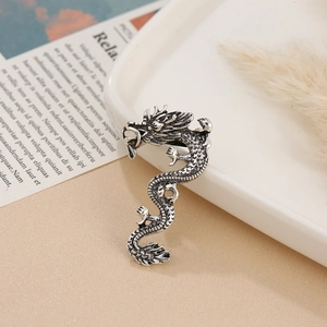 Detailed close-up of a vintage silver dragon brooch with intricate scales and antique finish