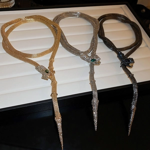 Close-up of snake head tassel necklaces featuring crystal scales in gold and silver