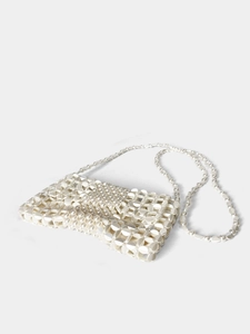 Close-up of white pearl woven handbag featuring detailed grid texture and long strap