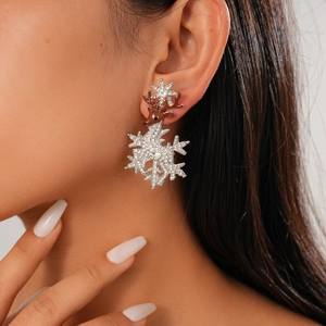 Close-up of reindeer and snowflake drop earring with glittering rhinestones on model