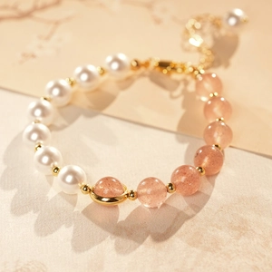 Detail of pearl and strawberry quartz bracelet with golden planet charm and lobster clasp