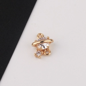 Macro detail of gold-plated planet charm with sparkling zircons and double hanging loops