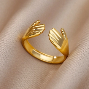 Close-up of golden adjustable hugging hands open ring on beige silk background
