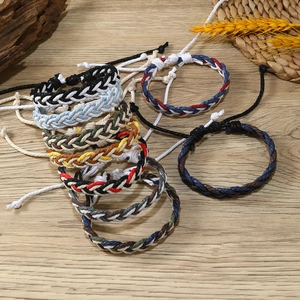 Close-up of handmade braided rope bracelets in various colors on rustic wood background
