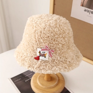 Gros plan détaillé d'un chapeau bob en laine d'agneau beige avec patch chiot et nœud