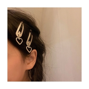 Close-up of two silver heart pendant metal hair clips worn on black hair for styling