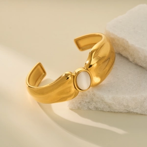 Detail of 18k gold plated open bangle with a polished white oval gemstone inlay