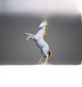Detail of a jumping horse sculpture in white and gold on a rock-textured base