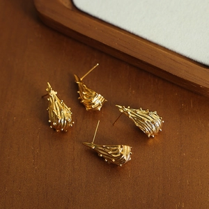 Minimalistische gouden druppeloorbellen met textuur op een houten achtergrond