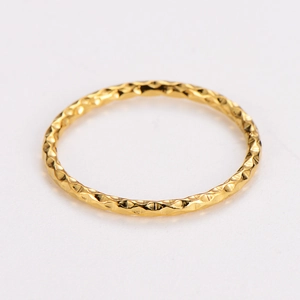 Macro shot of minimalist gold textured ring with diamond-cut sparkling facets on metal