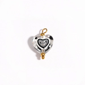 Detailed view of heart-shaped glass bead with black and white patterns and gold loop