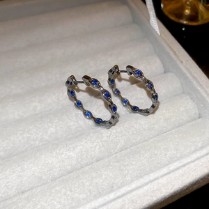 Detailed macro view of gunmetal hoop earrings set with marquise-cut deep blue zircons