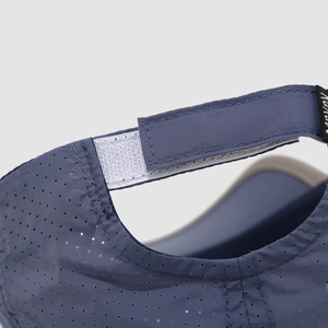 Close-up of the breathable perforated fabric and adjustable Velcro strap on the sports cap
