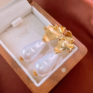 Detailed close-up of Baroque pearl earrings with gold geometric metal in a jewelry box