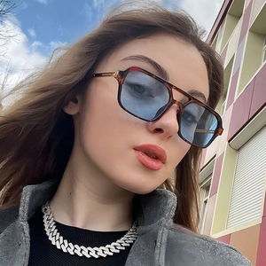 Close-up of tortoise shell aviator sunglasses paired with an iced-out silver Cuban chain