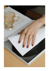 Detailed view of wide gold portrait coin ring and double band ring set on a hand