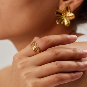 Close-up of golden hollow woven ring featuring natural stone on model's hand