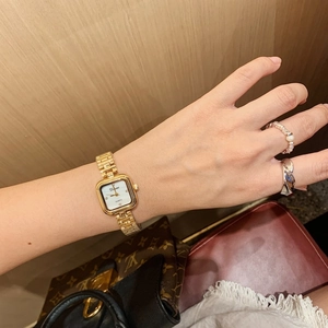 Close-up of a gold square women's watch with a shell dial on a model's wrist
