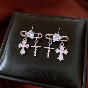 Detail view of silver zircon cross heart earrings on a black leather jewelry box background