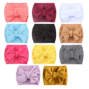 Set of eleven colorful baby headbands with large textured fabric bows in a grid layout