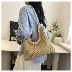 Detail of woven straw shoulder bag with white rope strap and lace trim on a model