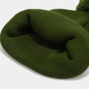 Detailed close-up of dark green ribbed knit beanie with thick wool-like texture