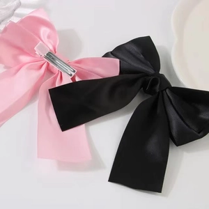 Pink and black satin bow hair clips with metal alligator clips on white background