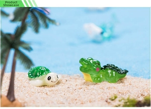 Miniature resin turtle and crocodile figurines on a beach sand micro landscape