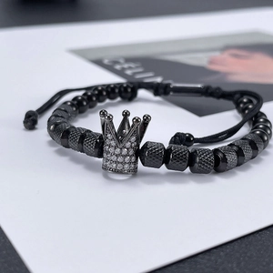 Detailed macro of beaded bracelet with silver crown charm and textured dark grey metal beads