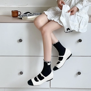 Close-up of JK style socks with ruffled edges and bow embroidery in black and white