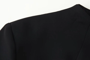 Close-up detail of the tailored shoulder and sleeve seam on a black stand-collar dress