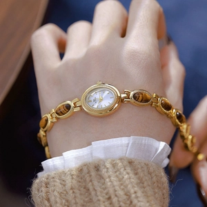 Detail of vintage gold bracelet watch for women featuring inlaid tiger eye stone accents