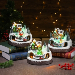 Luminous rotating Christmas village with music and miniature train on snowy landscape