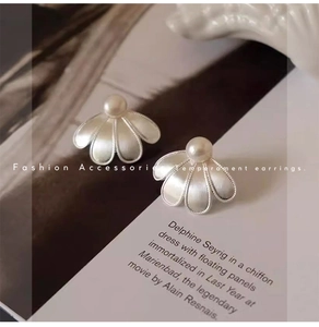 Detailed view of silver petal earrings with pearls on an elegant magazine background