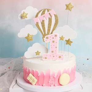 Close-up of pink hot air balloon and golden star cake toppers for first birthday decor