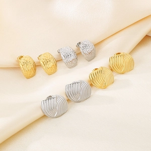 Close-up of gold and silver heart earrings with quilted texture on beige silk background