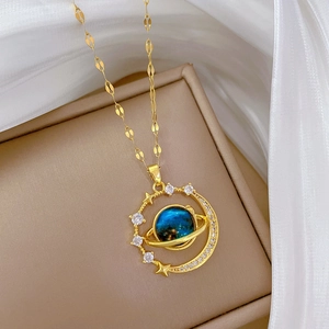Macro shot of gold planet necklace with blue center and sparkling crystals on a beige box